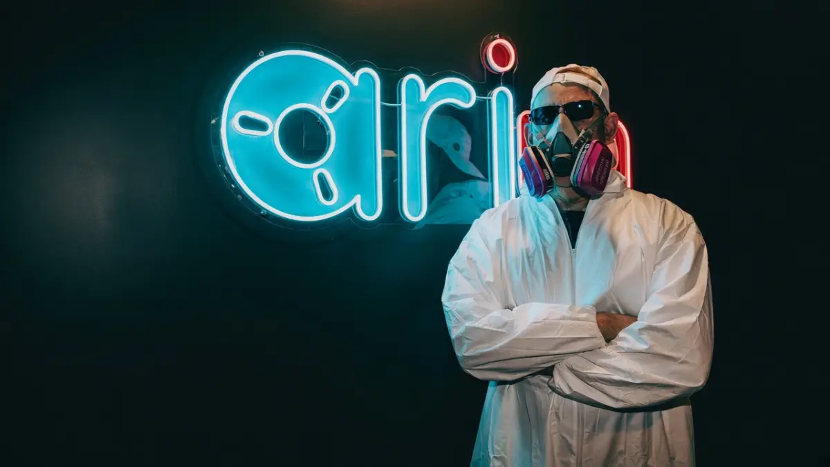 Brushstrokes in the hazmat suit beside a neon ari sign